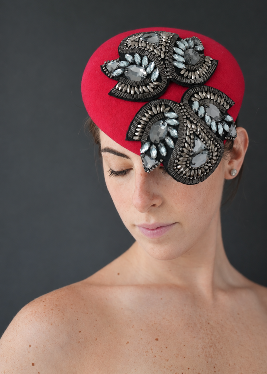 Valentina bright red percher hat decorated with ornate black and silver beaded floral embellishments, photographed against a dark gray studio