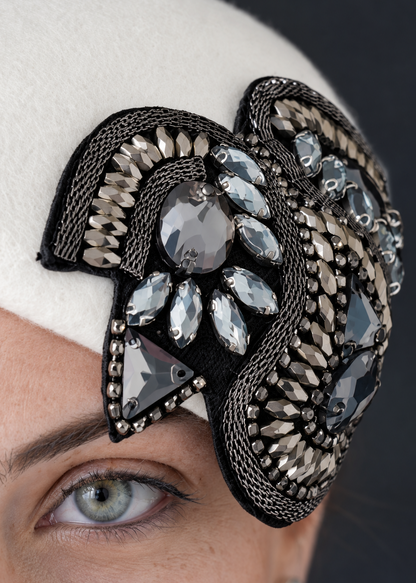 A close-up of the Bianca Percher hat, a ornate black fascinator headpiece embellished with silver mesh, clear rhinestones, and faceted gray and silver crystals.