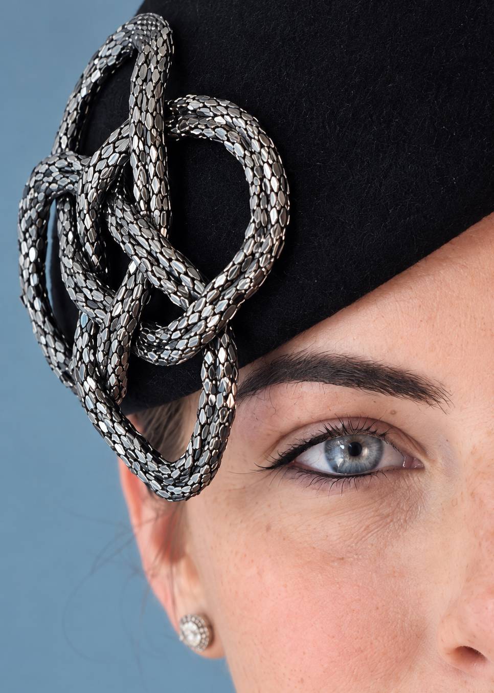 Close-up Fleur Percher fascinator hat with a large silver braided knot embellishment.