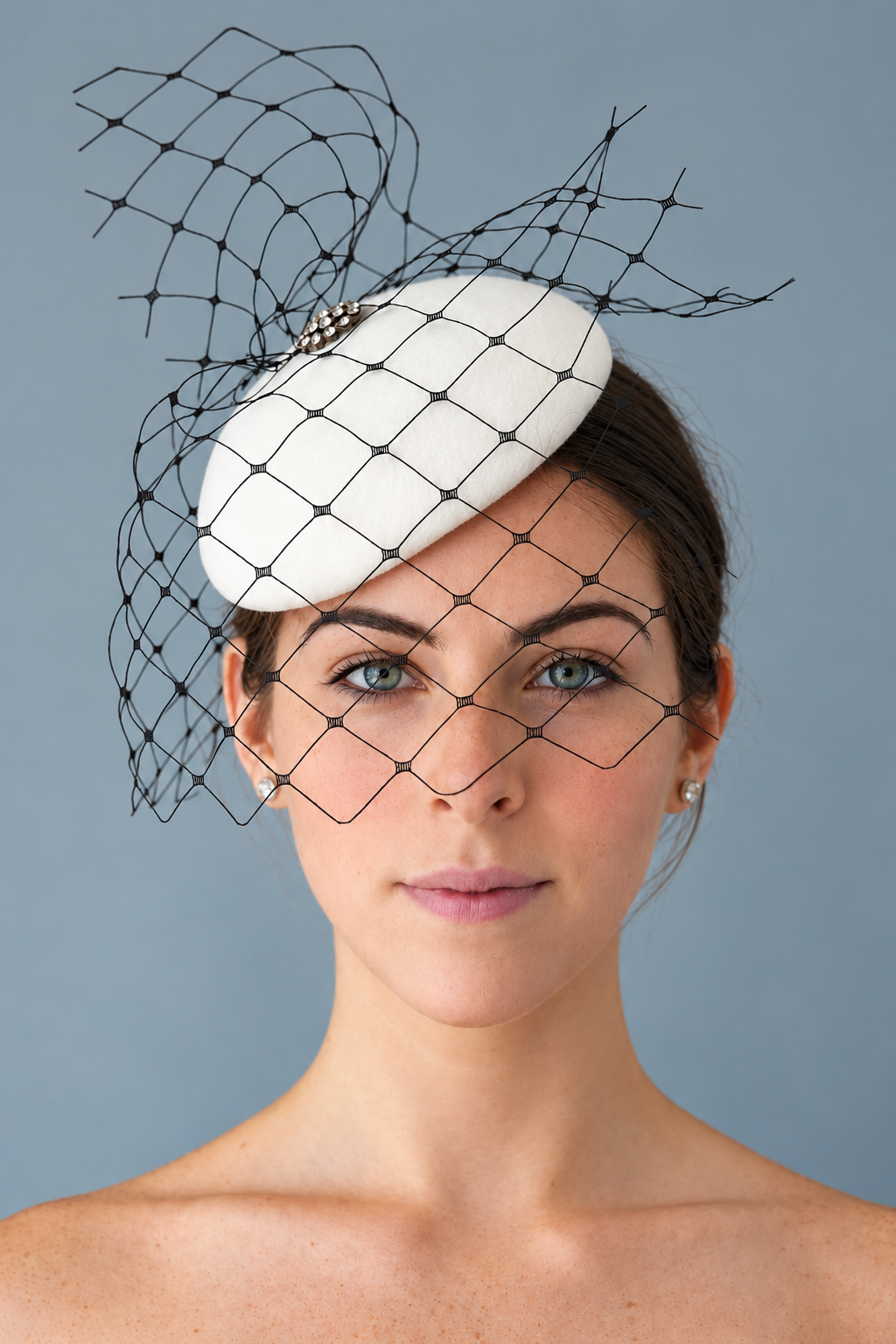 Model wearing the Lola white percher hat with a black birdcage veil, photographed against a solid blue-gray studio background.