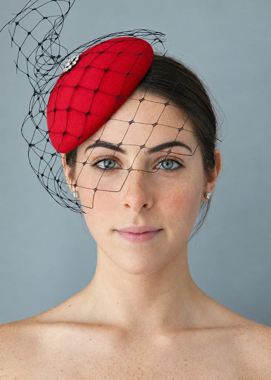 Model wearing the lola red hat with a black mesh veil, photographed against a plain gray studio background.
