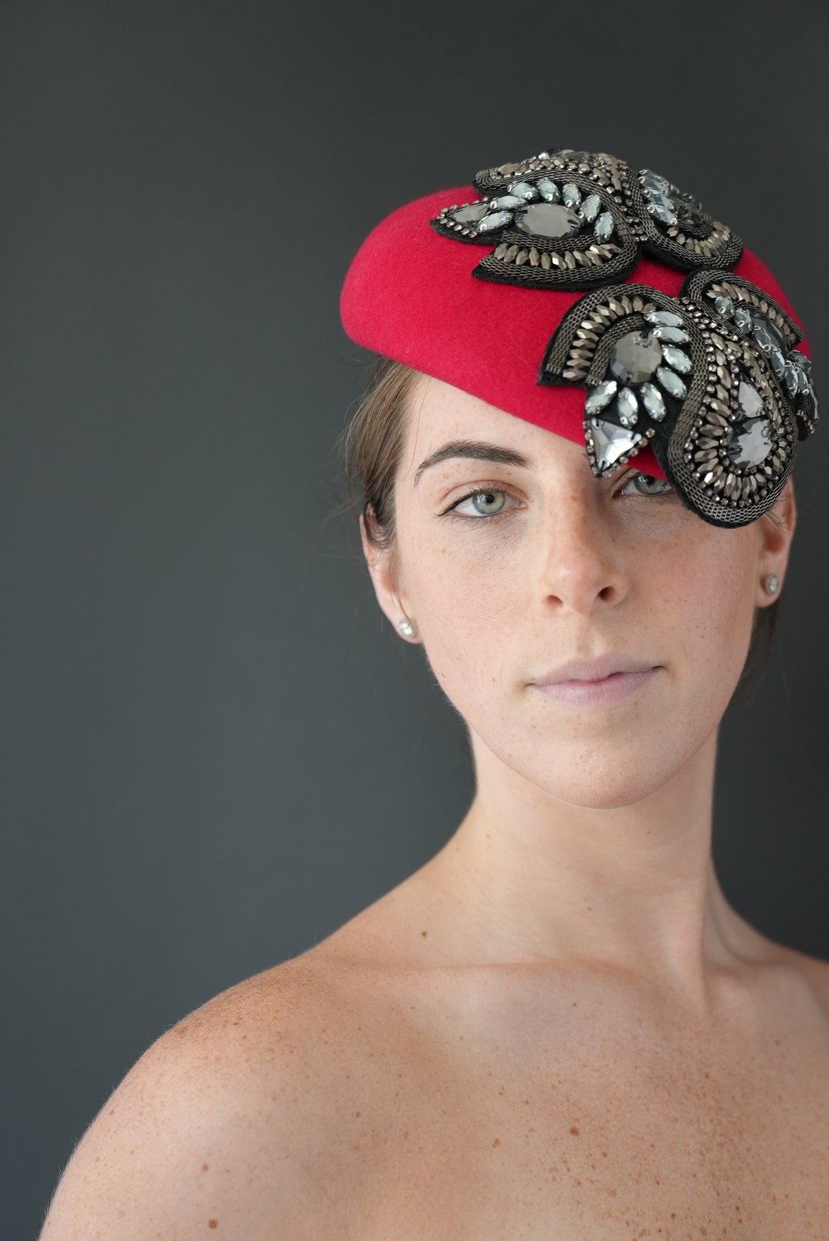 Valentina bright red percher hat decorated with ornate black and silver beaded floral embellishments, photographed against a dark gray studio background.